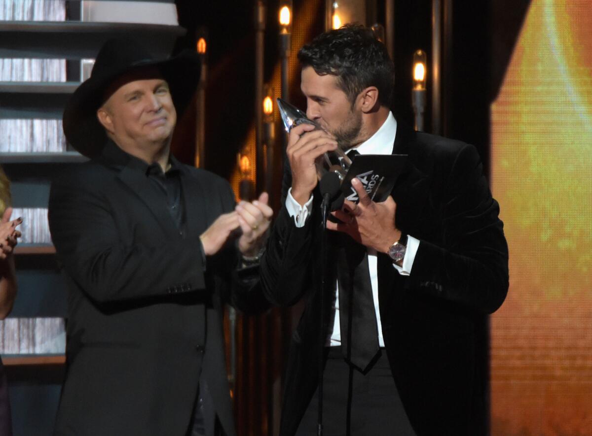 Garth Brooks, left, presents Luke Bryan with the award for Entertainer of the Year during the 48th CMA Awards in Nashville.