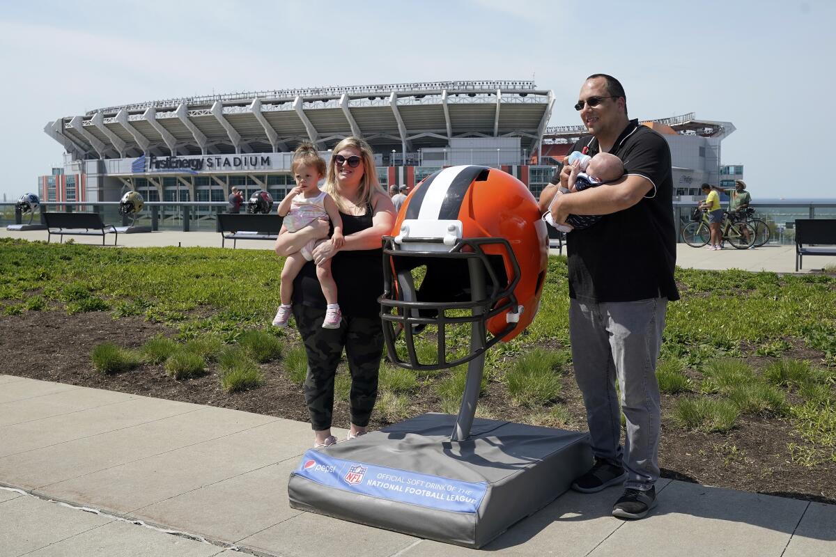 Fans pose for a photo with a large Cleveland Browns helmet outside FirstEnergy Stadium 