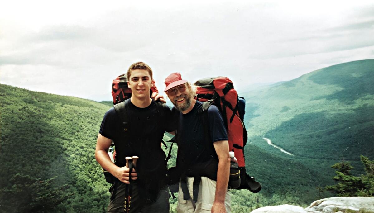 Two men wearing hiking gear and backpacks pose on a trail