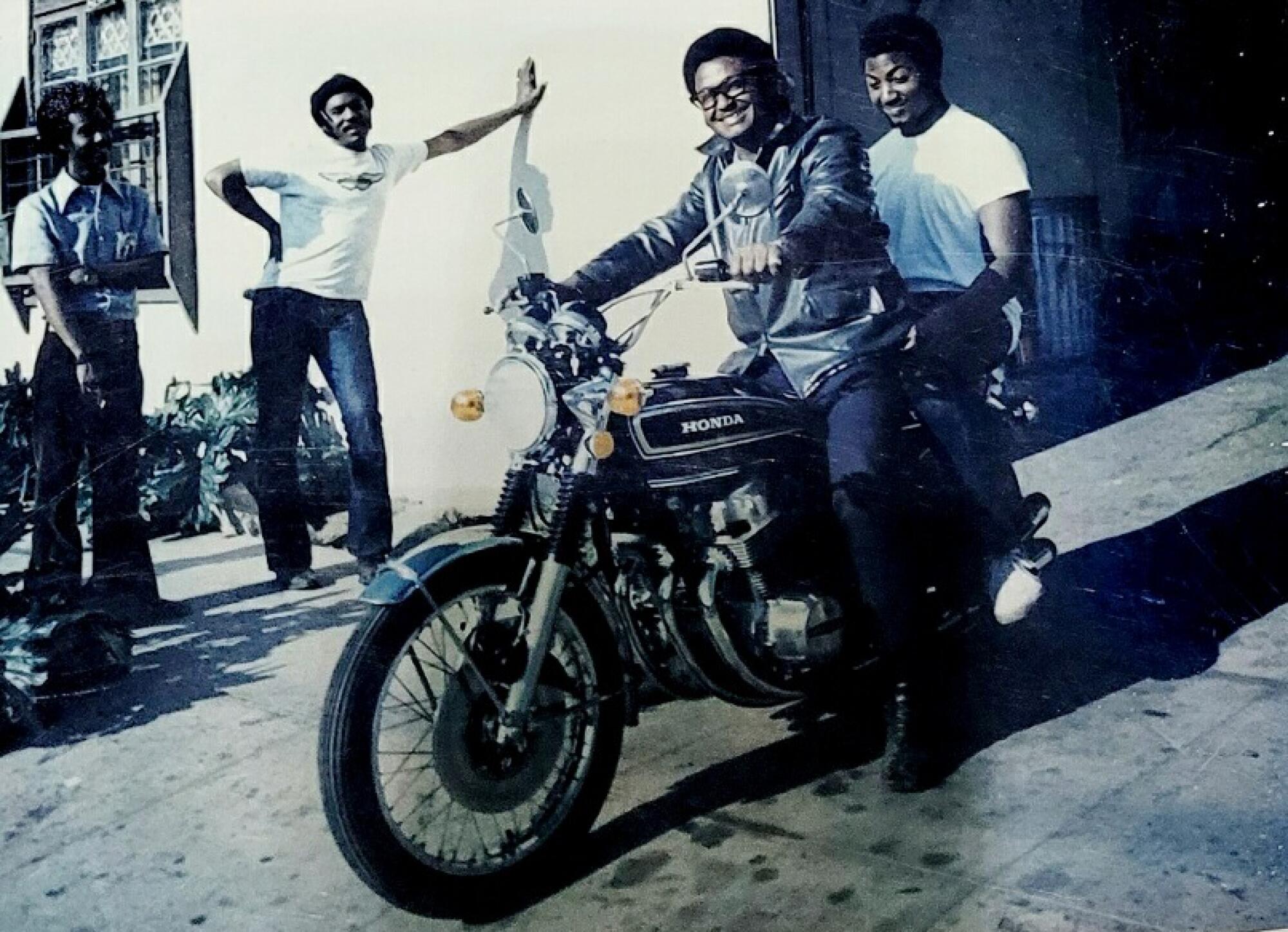 A father and son smile on a Honda motorcycle in a driveway