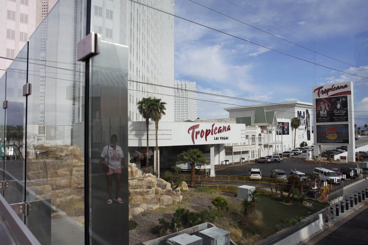 ARCHIVO - Una persona, reflejada en un vidrio, camina cerca del hotel-casino Tropicana de Las Vegas