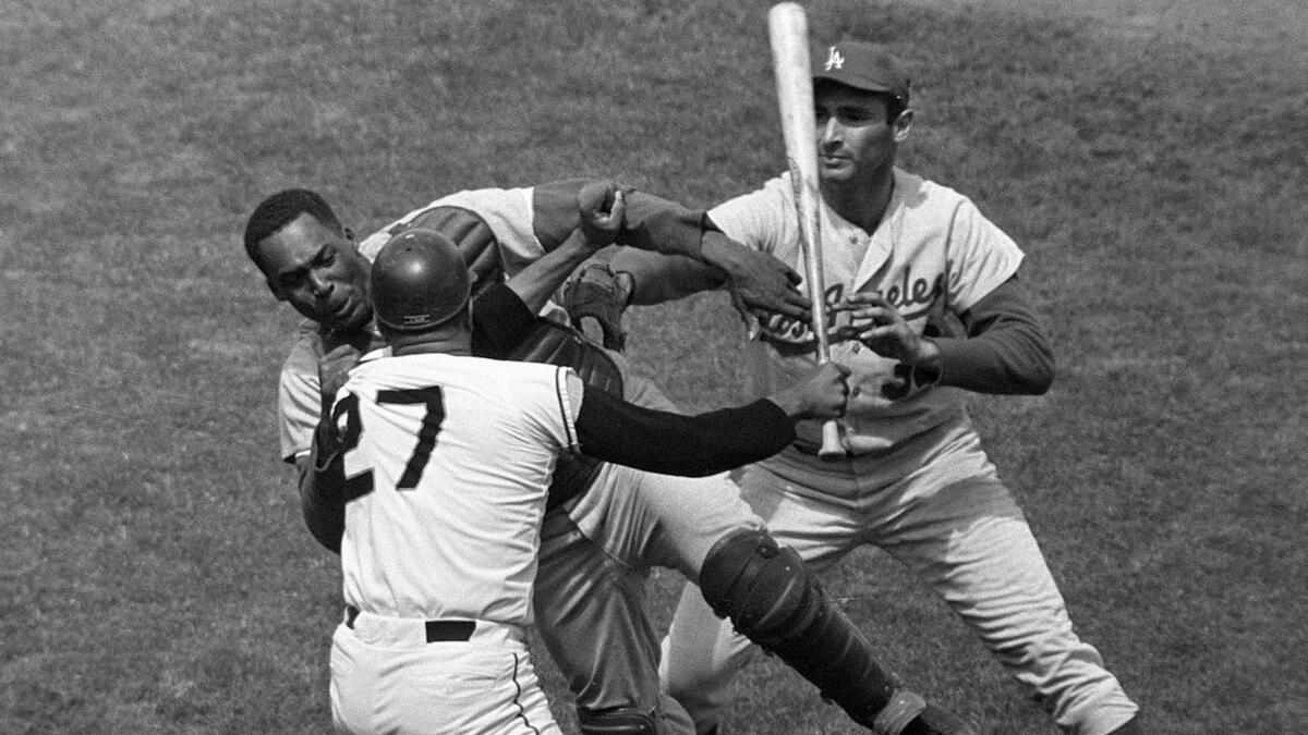 San Francisco Giants pitcher Juan Marichal, bottom left, swings a bat at Dodgers catcher John Roseboro as Sandy Koufax tries to intervene during a game at Candlestick Park on Aug. 22, 1965.