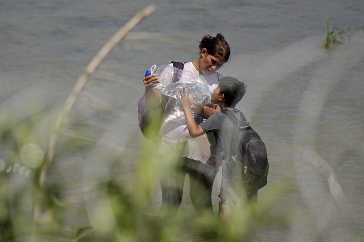 Dos migrantes se detienen para tomar agua 