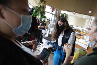 DALY CITY, CALIFORNIA - SEPTEMBER 17: San Mateo County Office of Community Affairs specialist Mitzy de la Pena Medina (R) hands out protective face masks to customers at the Top of the Hill Cafe on September 17, 2020 in Daly City, California. San Mateo County Board of Supervisors David Canepa launched the first-of-its-kind "mask mobile" that will provide face coverings, cleaning supplies and COVID-19 resources for residents in San Mateo County. (Photo by Justin Sullivan/Getty Images)