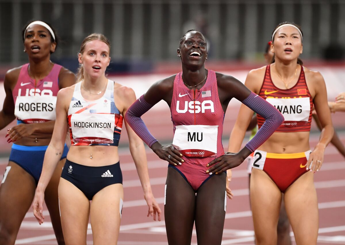 Athing Mu smiles on the track, flanked by competitors after the finish