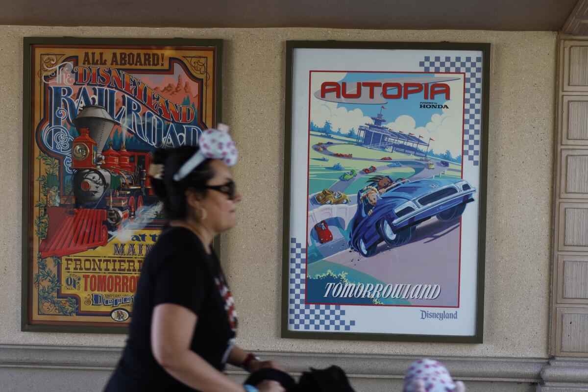 A guest walks past a poster advertising Autopia near the Disneyland entrance.
