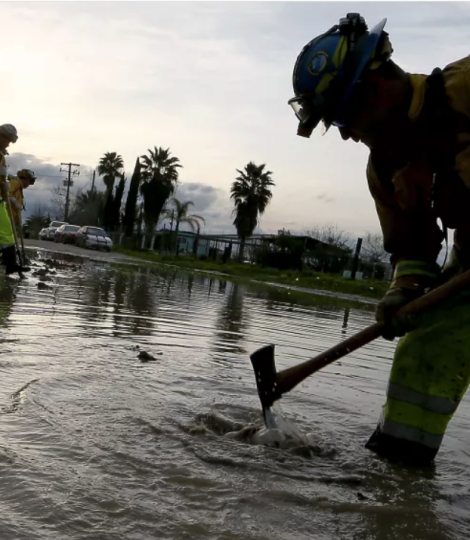 Un equipo de Cal Fire excava una zanja en una carretera inundada
