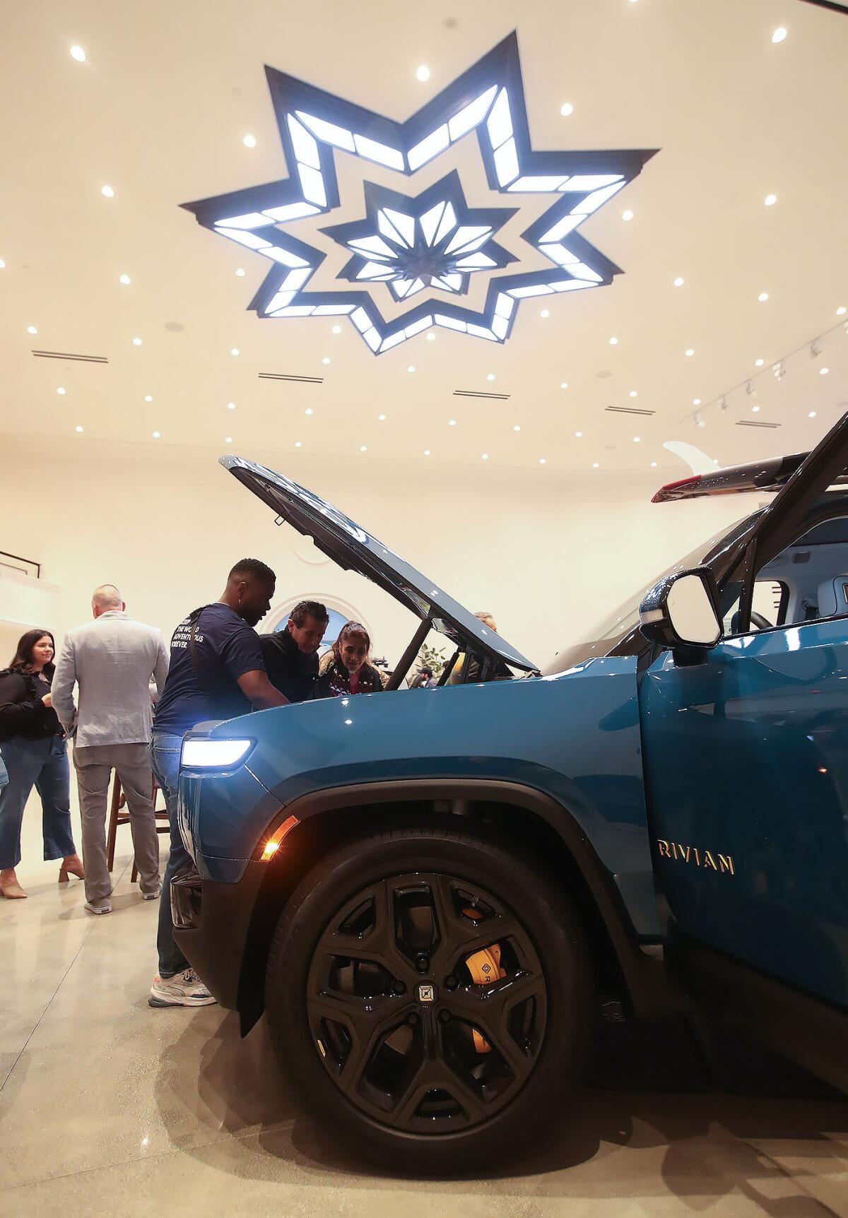 Guests look under the hood of a new Rivian electric truck in the showroom at the Rivian South Coast Theater in Laguna Beach.