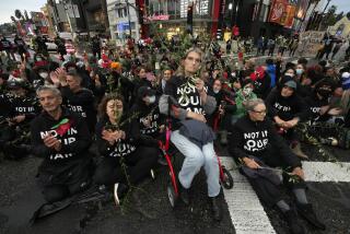 Demonstrators block an intersection during a sit-in demanding a cease-fire in the Israel-Hamas war in the Hollywood section of Los Angeles, Wednesday, Nov. 15, 2023. (AP Photo/Damian Dovarganes)
