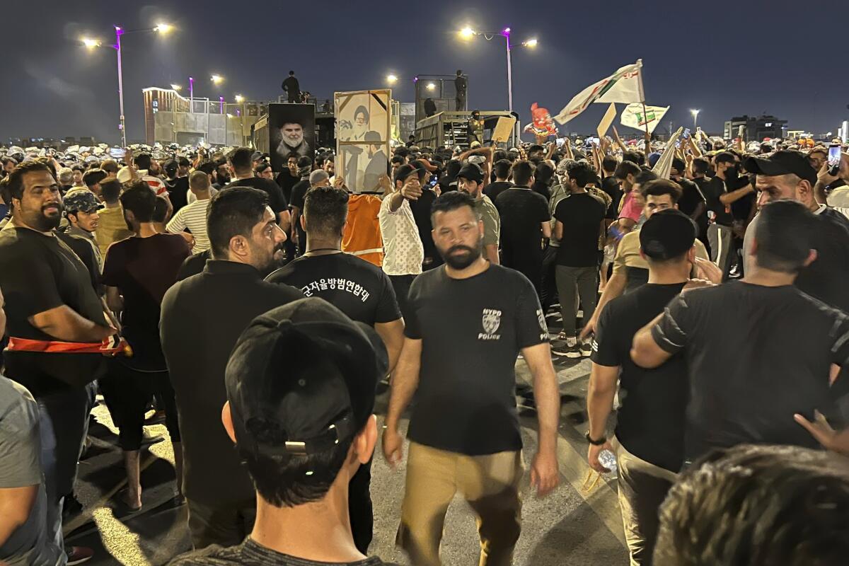 Protesters gather in Baghdad's Tahrir Square, some carrying Iraqi flags and images of Muqtada Sadr.