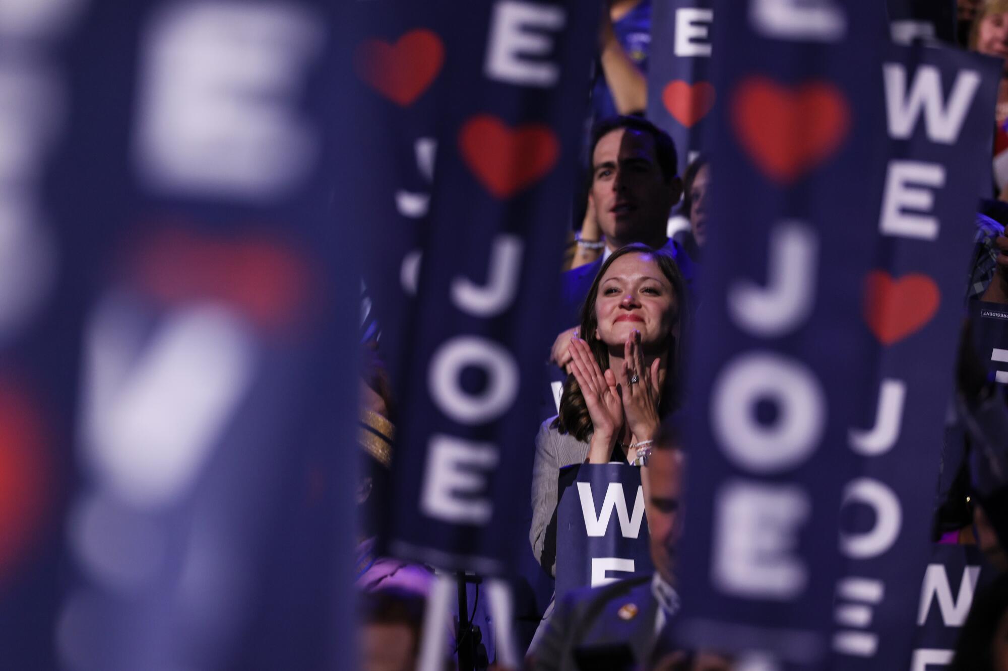 A delegate applauds between a crowd of "We [Heart] Joe" signs.