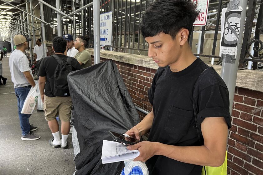 FILE — Dilan Jimenez reads text messages as he stands outside a shelter, after arriving on a chartered bus from Texas earlier in the day, Aug. 10, 2020, in New York. New York City's mayor says he plans to erect hangar-sized tents as temporary shelter for thousands of international migrants who have been bused into the Big Apple as part of a campaign by Republican governors to disrupt federal border policies. (AP Photo/Bobby Caina Calvan)