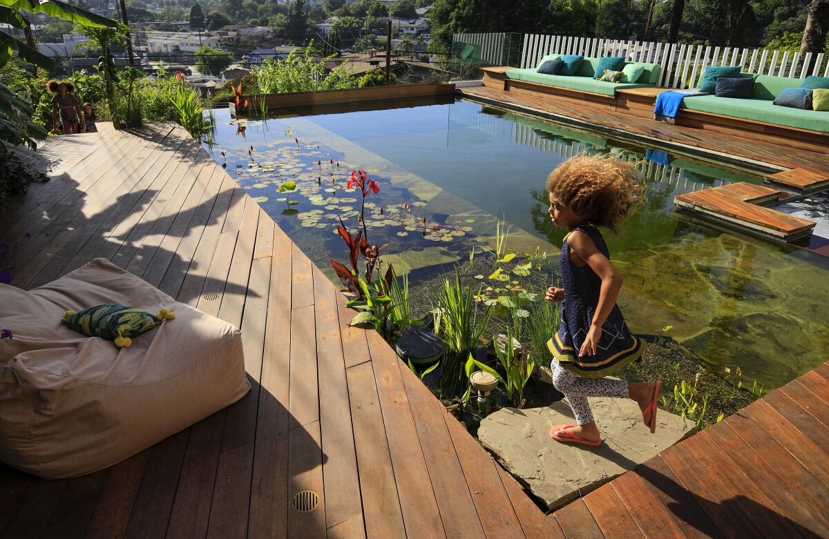 Xenia Caivano, 7, runs past the natural pool filtered by plants.