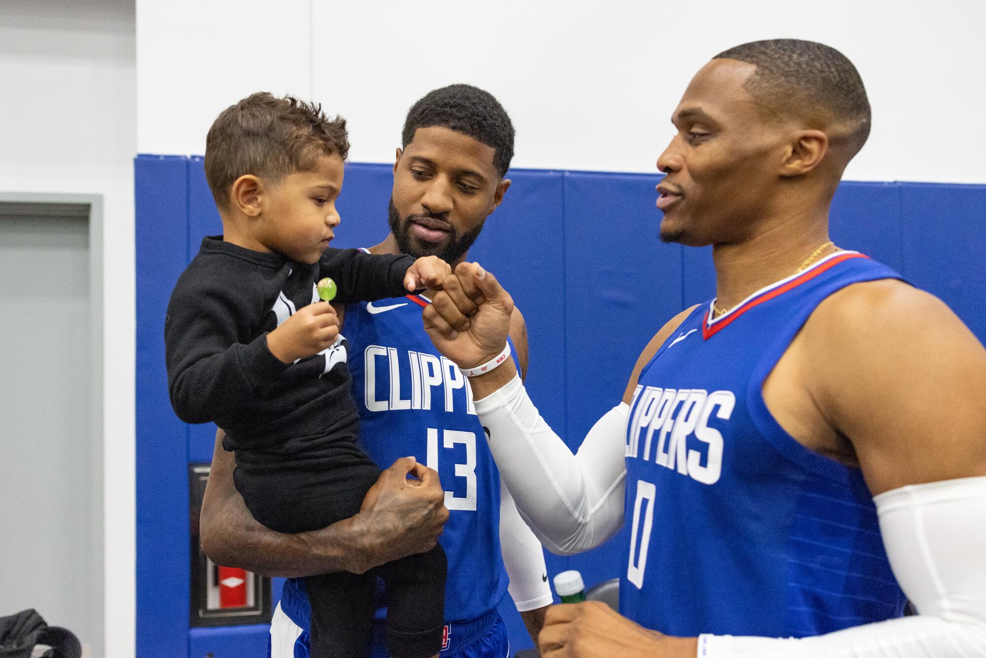 Russell Westbrook greets Clippers teammate Paul George and his son, Paul Vuk, during media day.