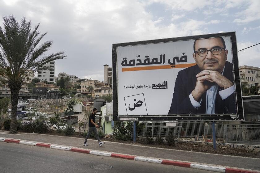 A man walks by an election campaign billboard showing Sami Abu Shehadeh, head of the nationalist Balad party, in the northern Israeli city of Umm al-Fahm, Friday, Oct. 21, 2022. Israel’s Palestinian citizens, a minority whose voice is often drowned out, delegitimized or disparaged in Israel’s noisy politics, could hold the key to breaking the country’s political deadlock. Israel heads to the polls Nov. 1 for the fifth time in less than four years. (AP Photo/Mahmoud Illean)