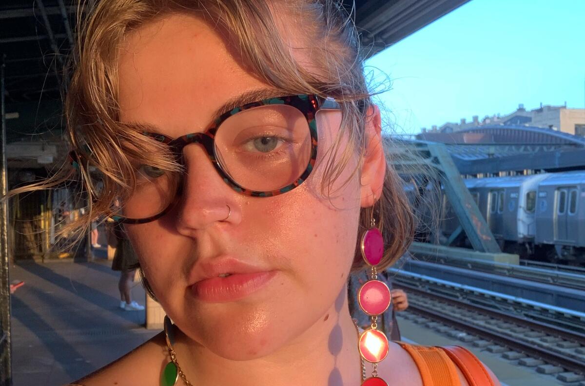 Self-portrait of Julia Carmel with glasses near a train 