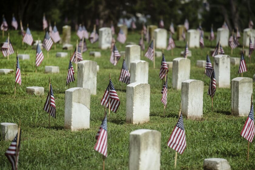 Flags are placed near headstones at the Vicksburg National Cemetery during the Memorial Day flag placement event in Vicksburg, Miss., Friday, May 28, 2021. About 40 volunteers placed nearly 1,700 flags. (Eric Shelton/The Clarion-Ledger via AP)