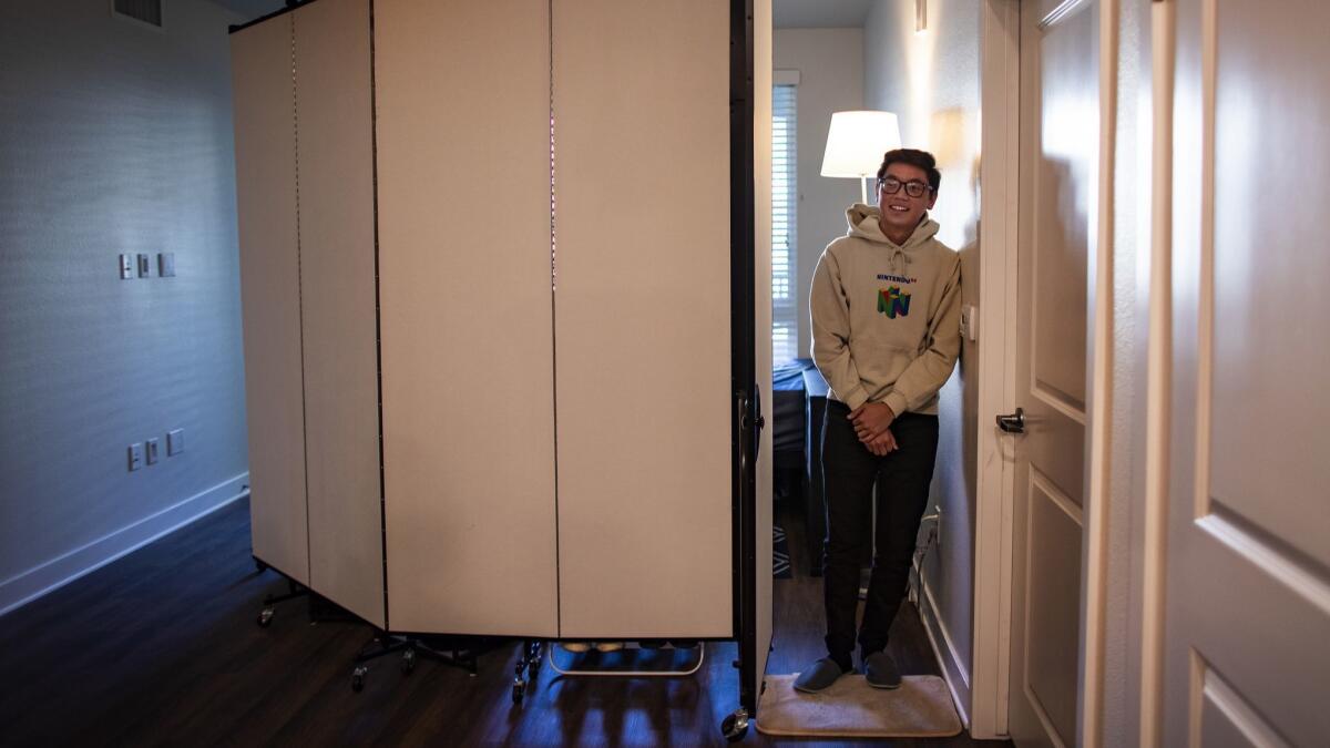 Chris Cacho at the door of his bedroom, a subdivided living room, in the Glendale apartment he shares with two roommates.