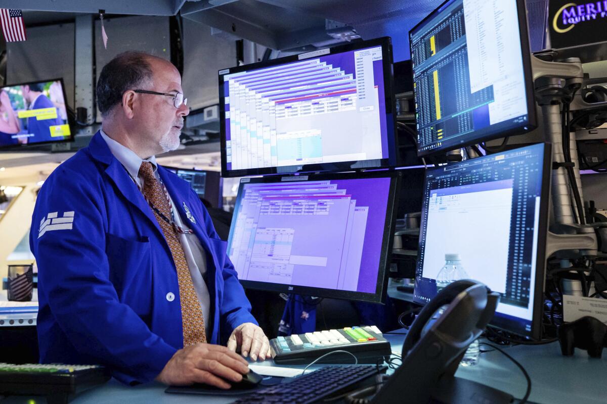 A man in a blue jacket is surrounded by computer screens.