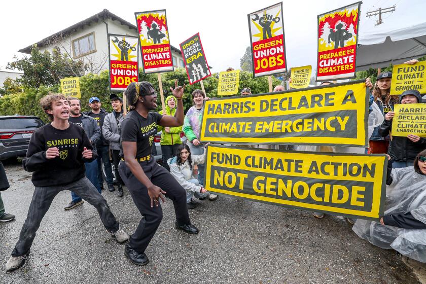 Brentwood, CA, Sunday, April 14, 2024 - Sunrise Movement protesters gather near VP Harris' Brentwood home calling on her to urge President Biden to declare a climate emergency. Simon Aron, left and Josiah Edwards, center lead a chant. (Robert Gauthier/Los Angeles Times)
