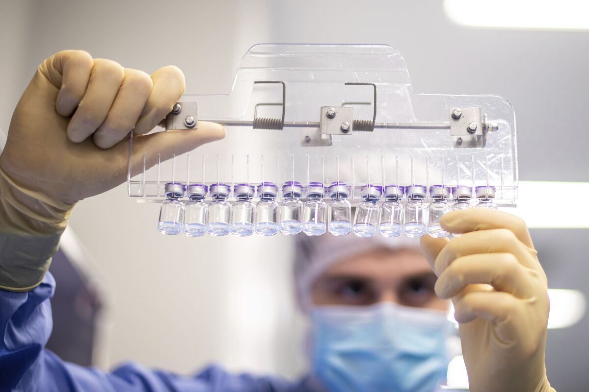 A technician inspects filled vials of the Pfizer-BioNTech COVID-19 vaccine. 