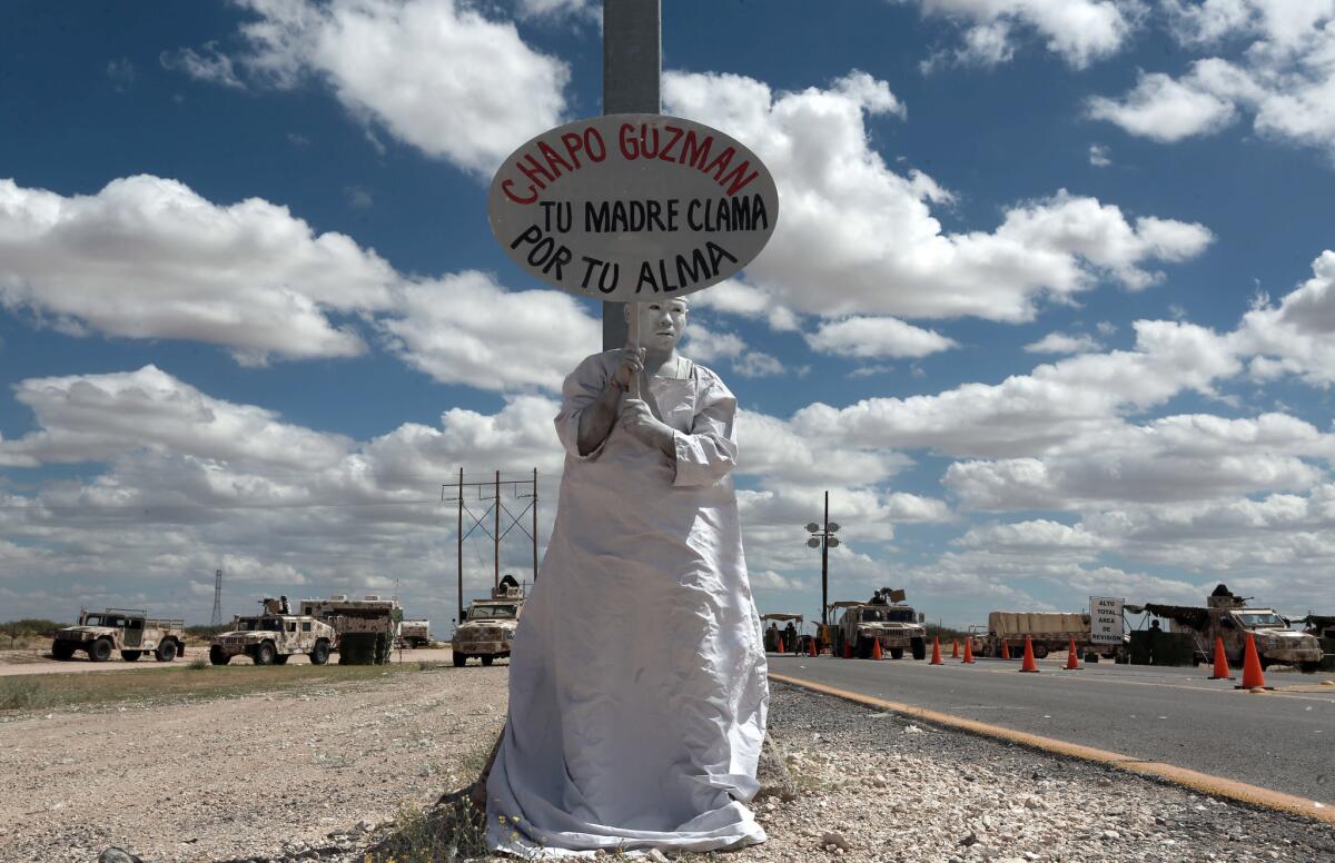 A member of Los Angeles Mensajeros holds a sign reading in Spanish "Chapo Guzman, your only mother prays for your soul" outside the prison where Guzman is being held in Ciudad Juarez, Mexico.