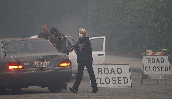 La Ca?ada Flintridge resident Patti Maloof sports a mask at a checkpoint on Ocean View Boulevard as she keeps a close eye on the burning hills near her home.