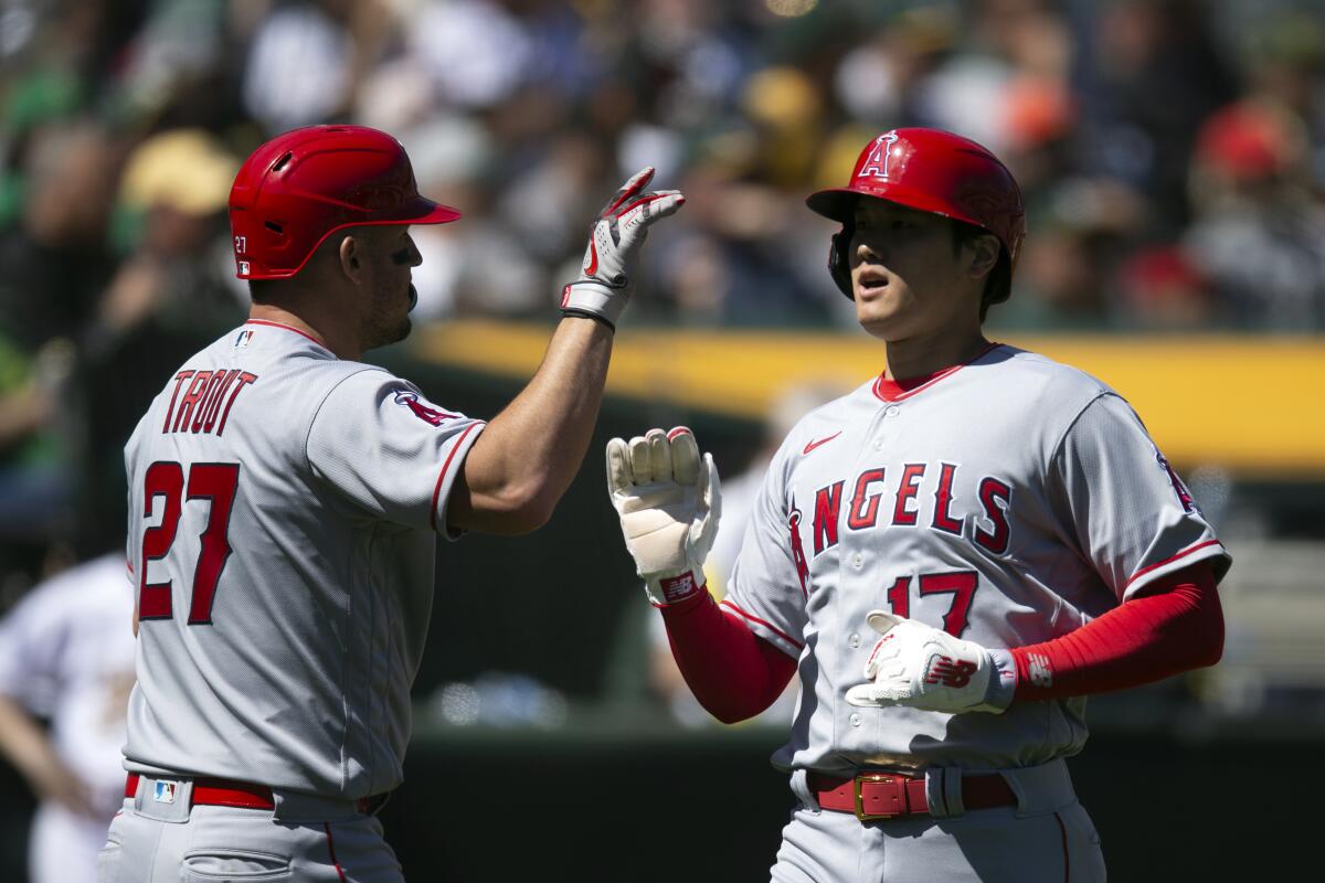 The Angels' Mike Trout, left, greets Shohei Ohtani after they scored on Jake Lamb's single on April 1, 2023.