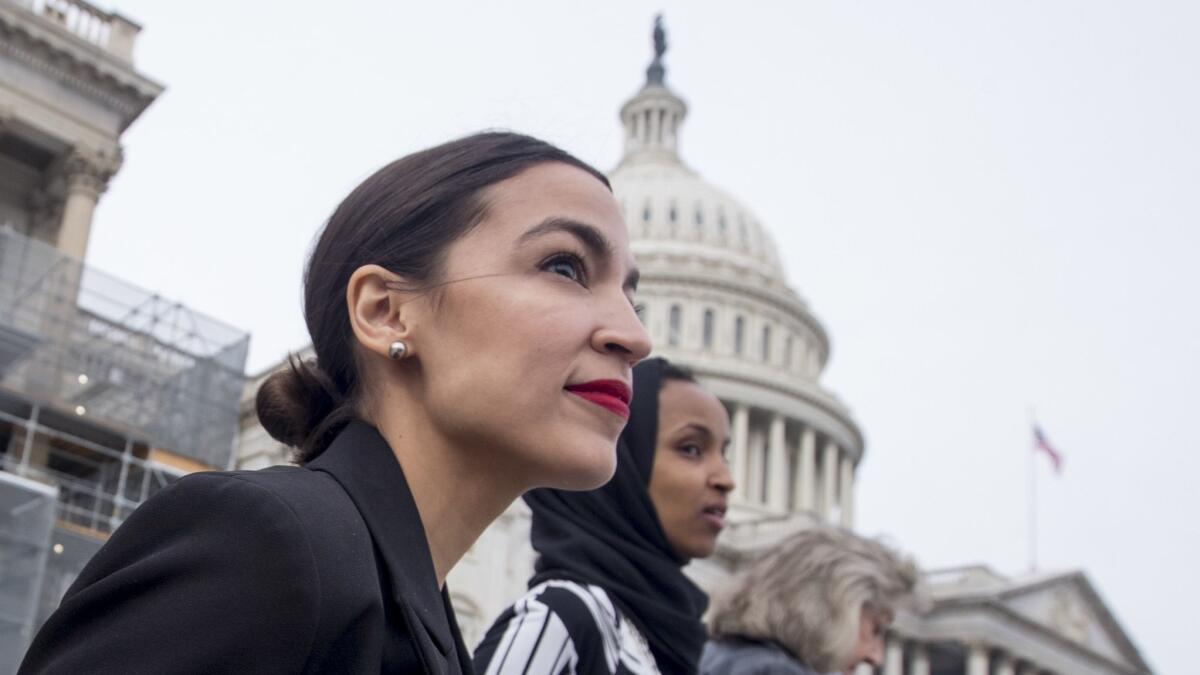 Rep. Alexandria Ocasio-Cortez, left, and D-N.Y., Rep. Ilhan Omar, D-Minn., center, walk down the House steps on Capitol Hill in Washington on Jan. 4.