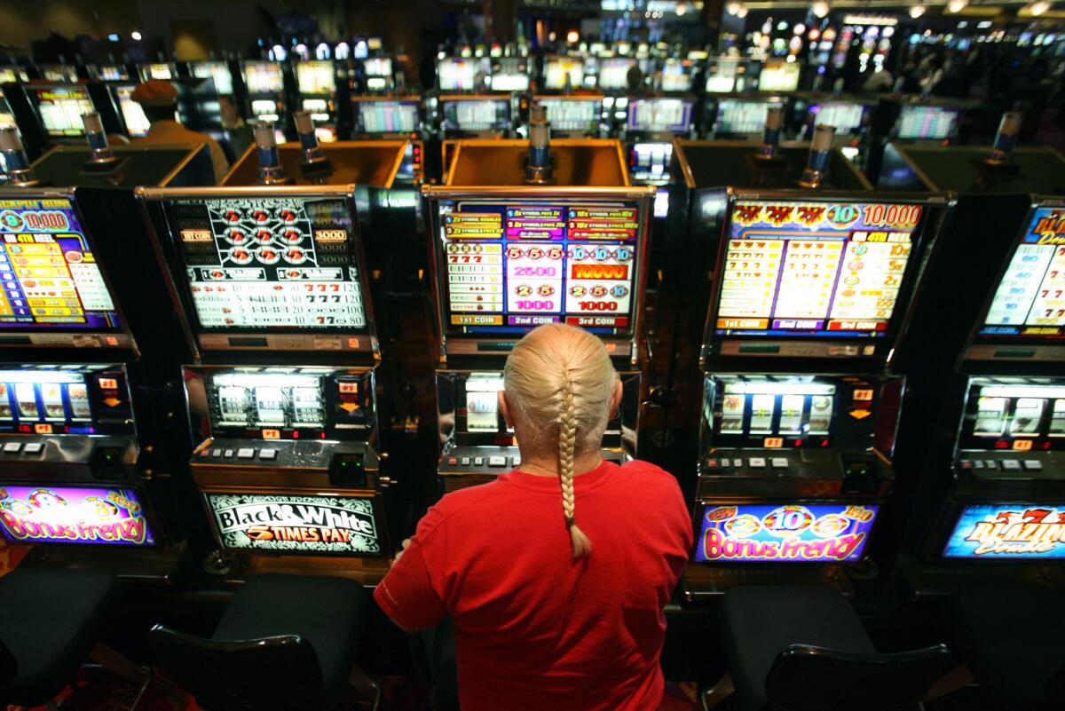 A gambler puts money into a slot machine at casino in Riverside County, one of four counties that were audited.