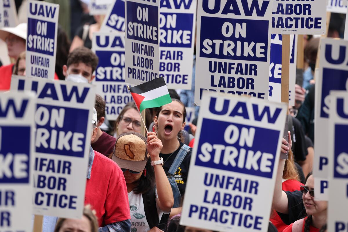 People march holding "UAW on Strike" signs 