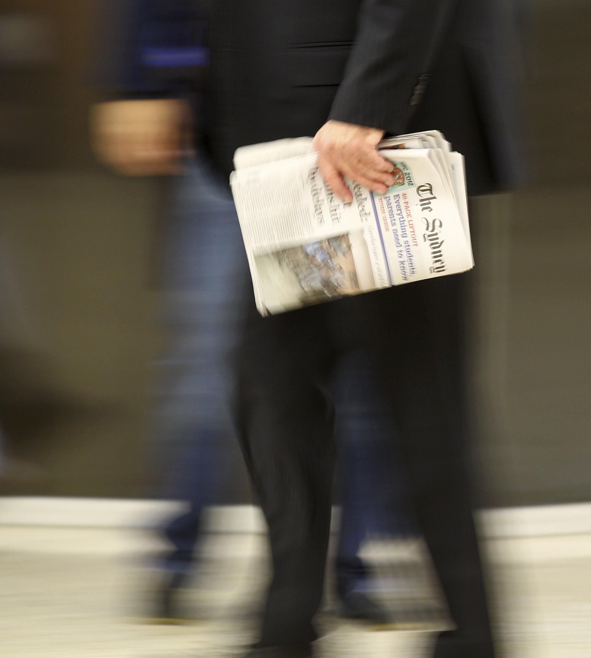 A man carries a newspaper.