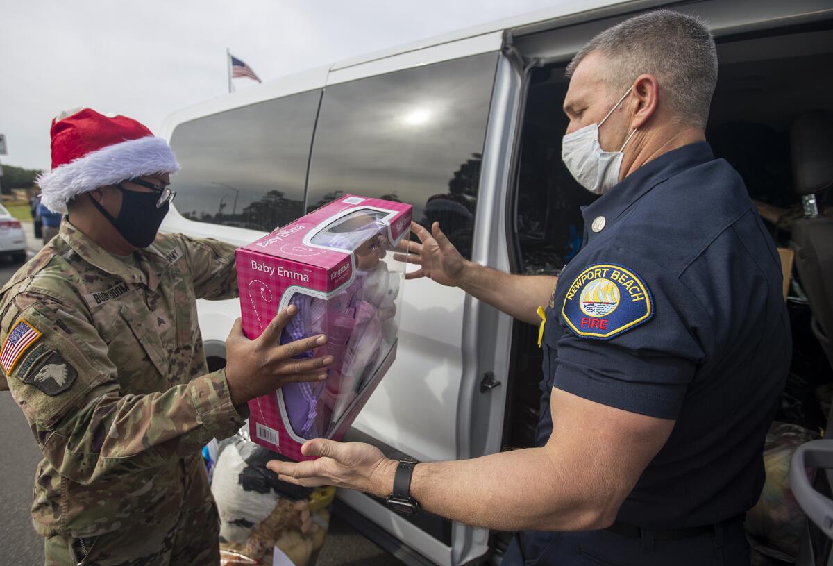 Sgt Mickey Boonyodom, left, hands a toy to Cpt. Ty Lunde,