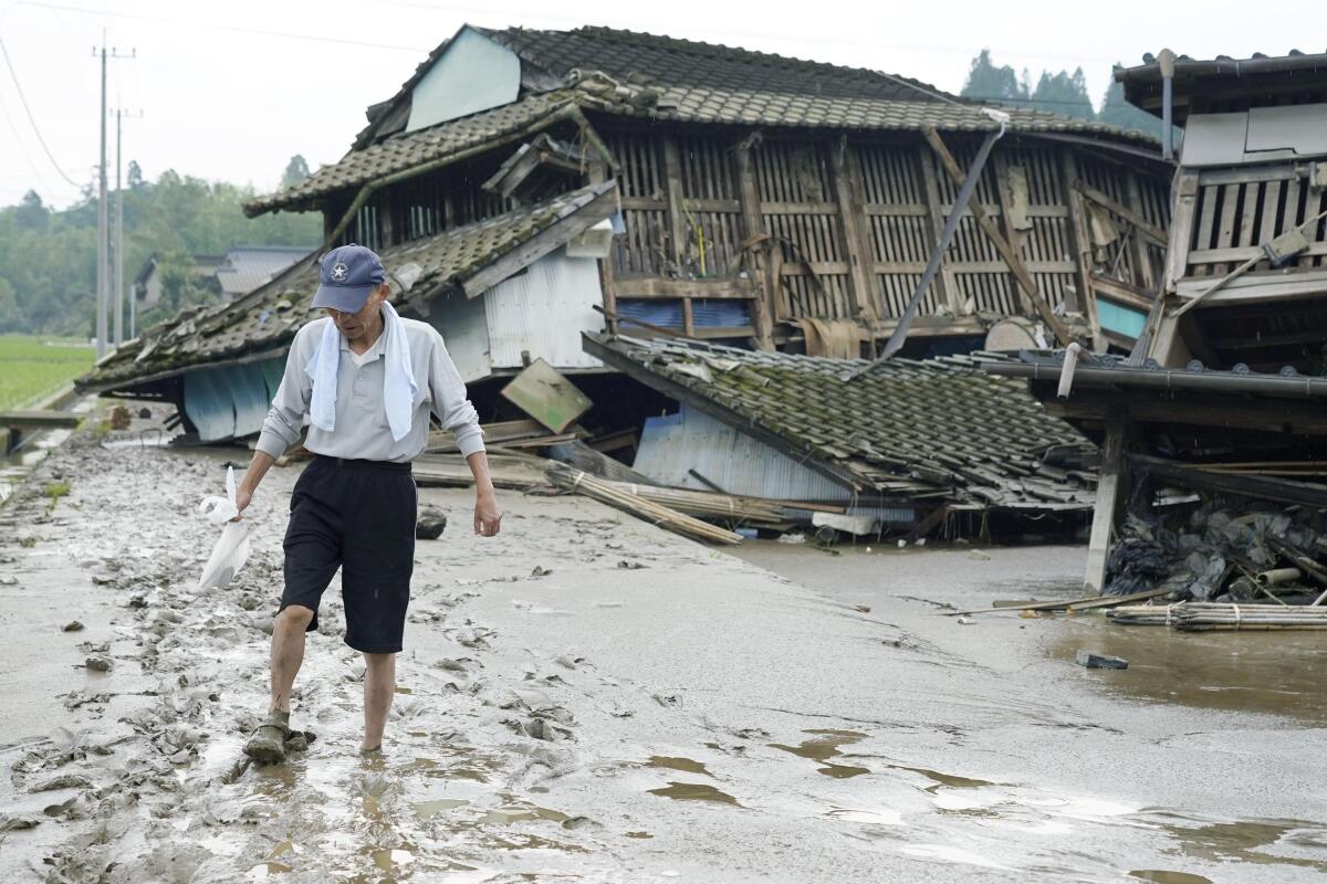 A man walks on muddy road past houses damaged by flood in Kuma village, Kumamoto prefecture, southwestern Japan.