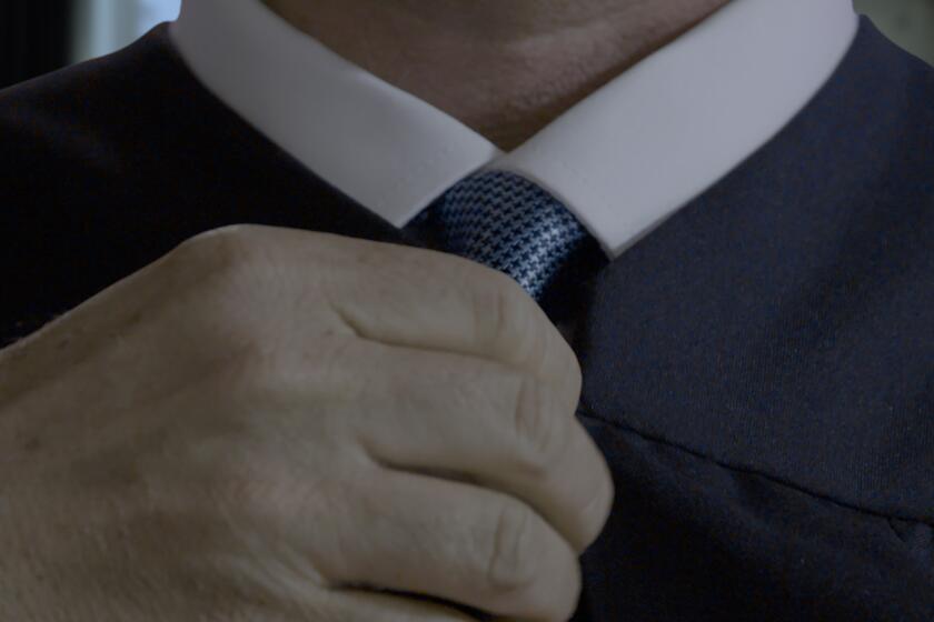 A close-up of a man adjusting his tie