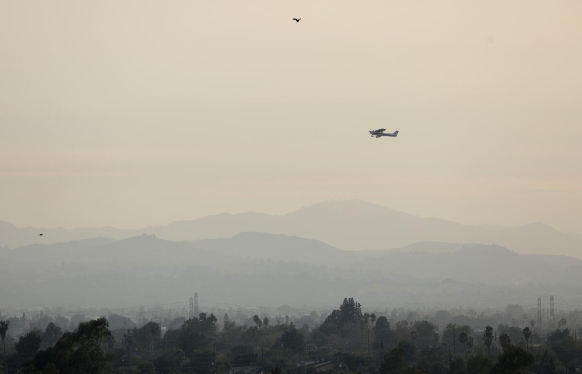 A plane takes off in a smoky sky
