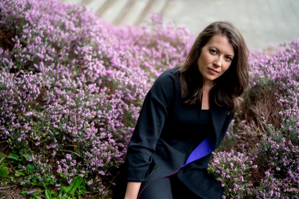 A woman sits in a patch of purple flowers.