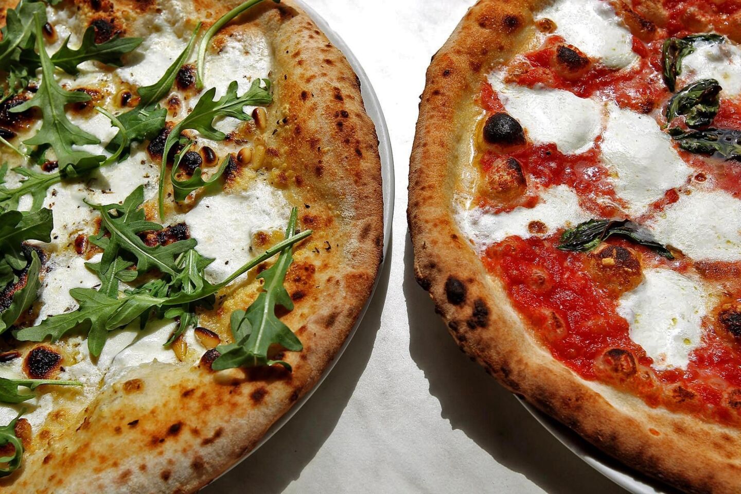 A pizza bianca with mozzarella, pine nuts and arugula, left, and a pizza margherita, right, are offered at 800 Degrees Neapolitan Pizzeria in Westwood Village.