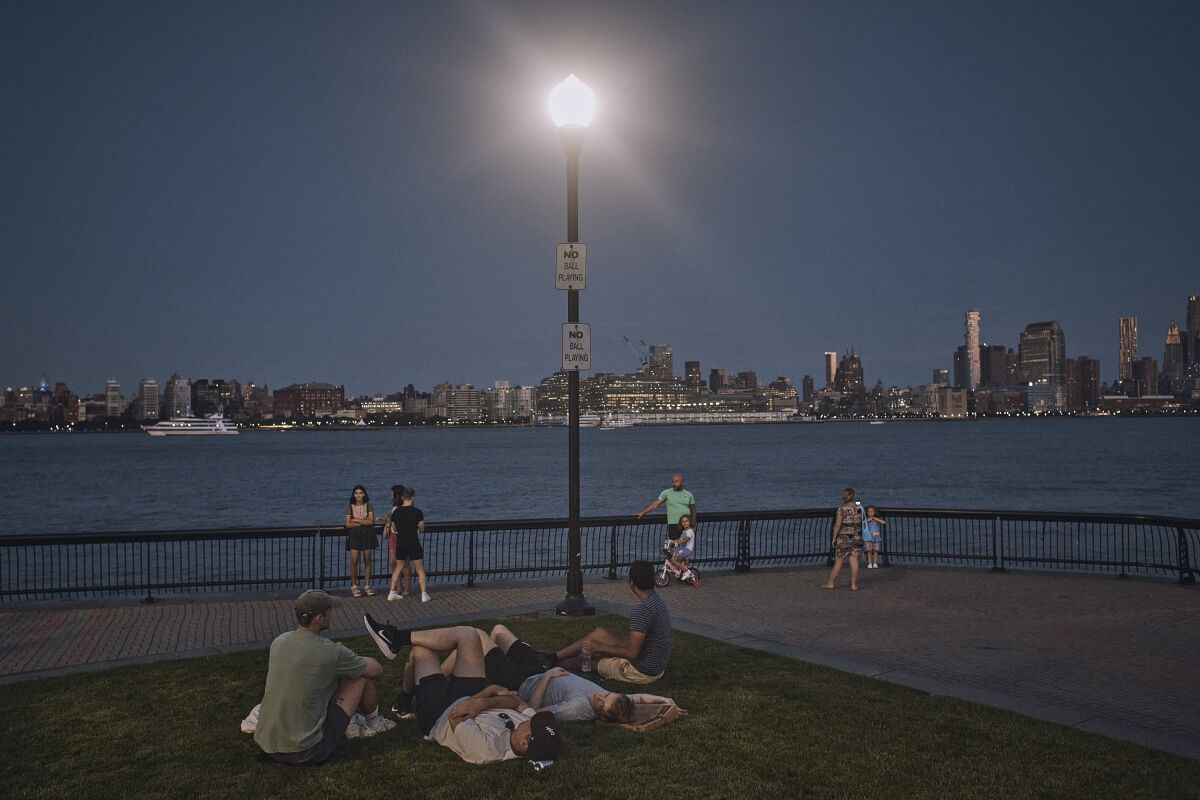 FILE - People spend time at the park at dusk during a summer heat wave, July 21, 2022, in Hoboken, N.J. The continental United States in July set a record for overnight warmth, providing little relief from the day’s sizzling heat for people, animals, plants and the electric grid, meteorologists said. (AP Photo/Andres Kudacki, File)