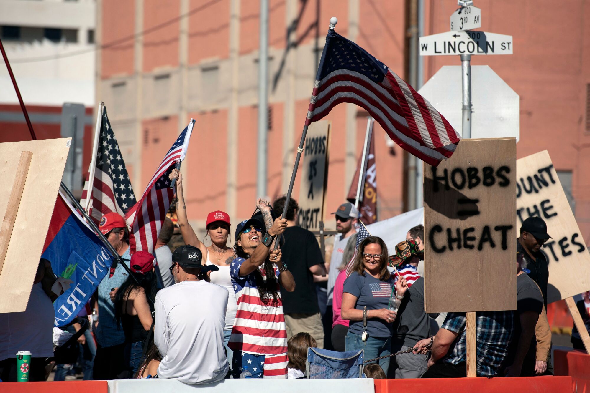 Demonstrators hold American flags and signs during a rally in Phoenix.