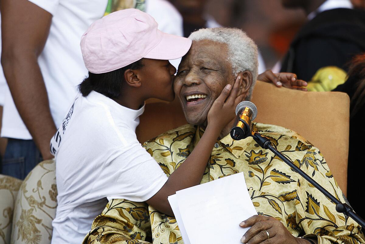 The late former South African President Nelson Mandela, right, laughs as he receives a kiss from one of his grandchildren on August 02, 2008, after giving a speech at Loftus stadium in Pretoria.