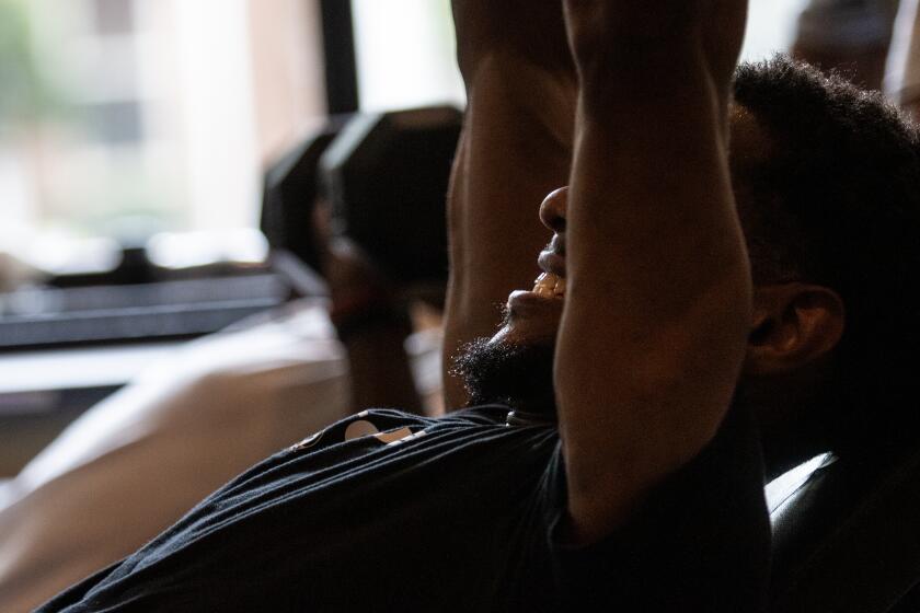 Paris Cokely lifts free weights as part of a rigorous physical training boot camp run by Sakai Harrison on Wednesday, July 29, 2020, in Atlanta. Harrison moved to New York to try to make it as a personal trainer and designer - but his gym shuttered early in the pandemic, and after weeks of struggling to both pay the rent and put food in his fridge, he knew what he had to do. He moved back to Georgia for greater stability. (AP Photo/Ron Harris)