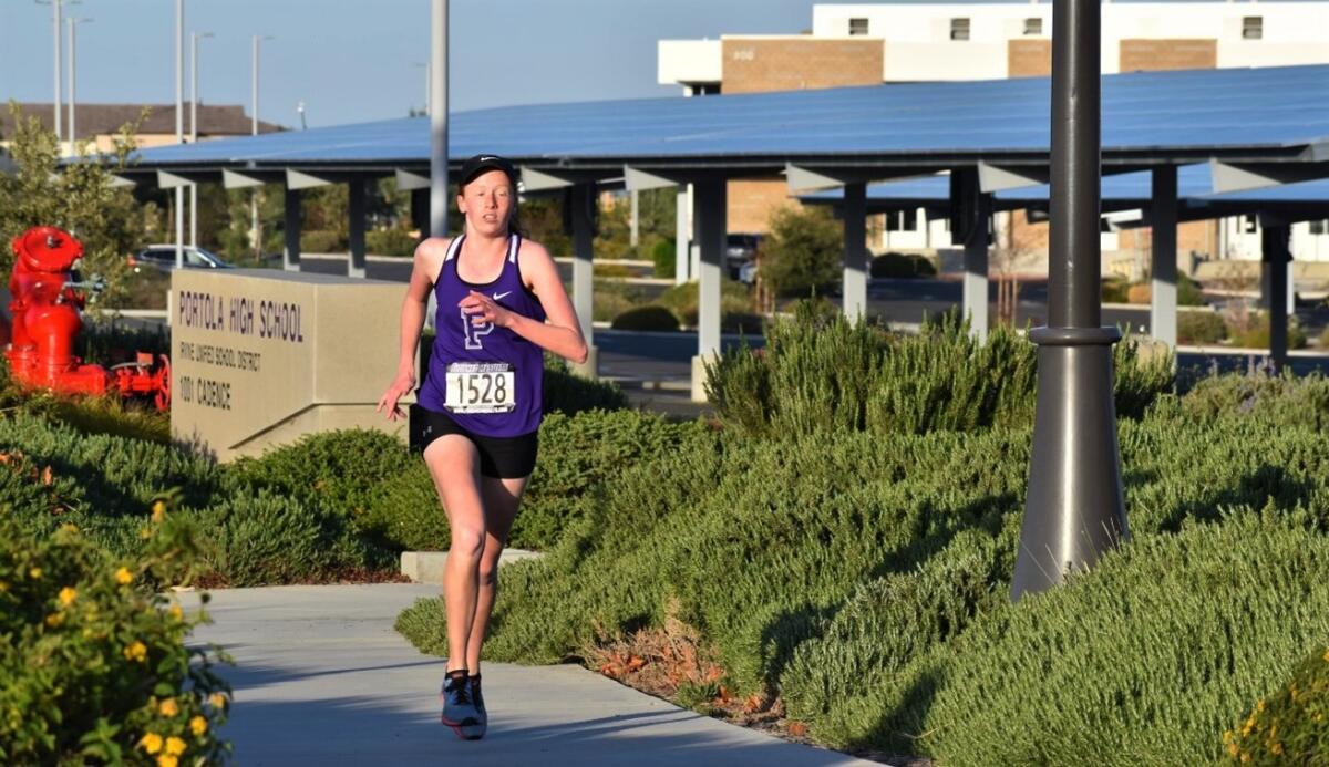 Jadyn Zdavanage runs past the sign at Portola High.