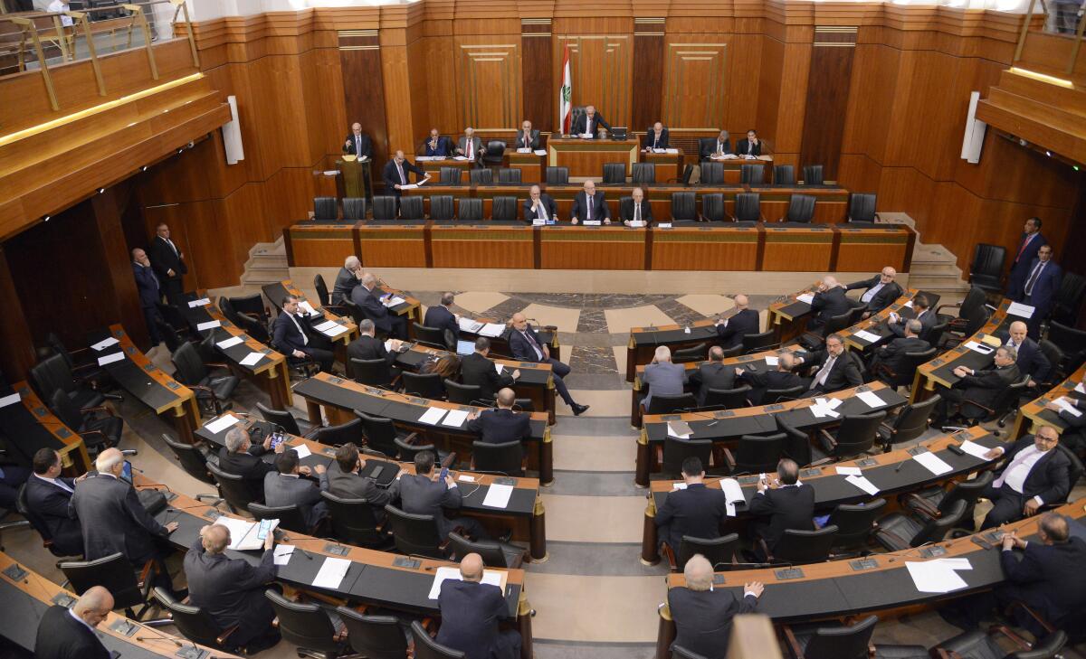 In this photo released by the Lebanese Parliament media office, Lebanese lawmakers and some ministers including Prime Minister Najib Mikati, center, headed by the Parliament Speaker Nabih Berri, top center, attend a parliament session, in Beirut, Lebanon, Tuesday, Oct. 18, 2022. Lebanon's parliament approved late Tuesday amendments to a banking secrecy law that has been a key demand of the International Monetary Fund amid the country's historic economic meltdown. (Hassan Ibrahim/Lebanese Parliament media office via AP)