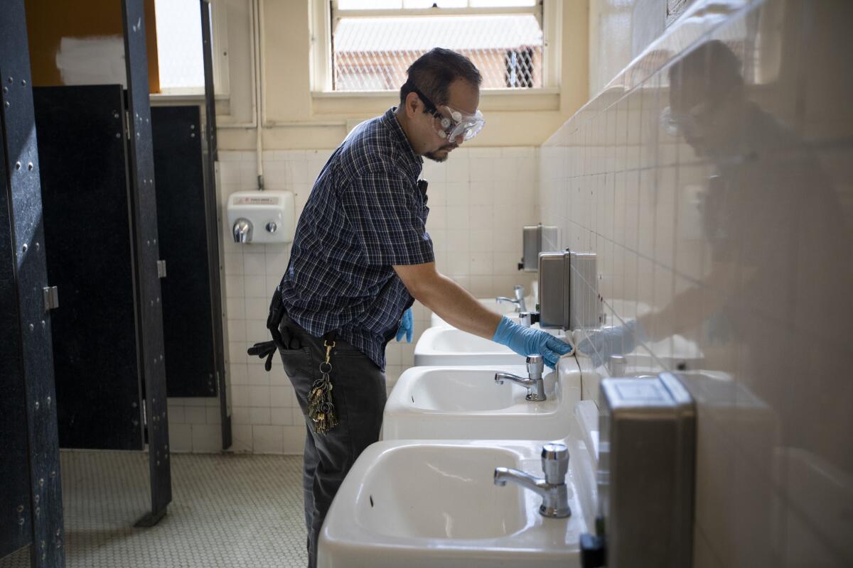 A man wipes down sinks in a bathroom