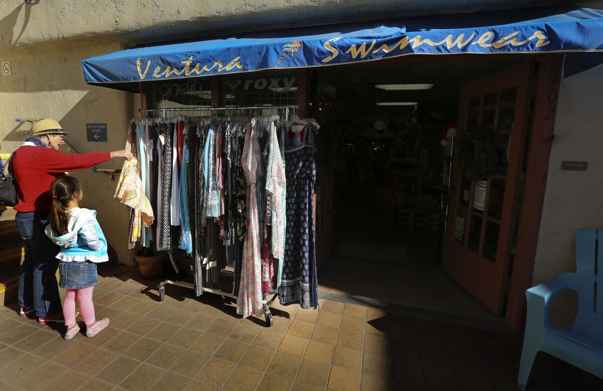 Shoppers check out the rack in front of the entrance to Ventura Swimwear at Ventura Harbor Village.
