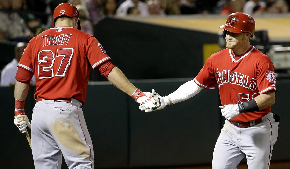 Los Angeles Angels' Kole Calhoun, right, is congratulated by Mike Trout after hitting a solo home run off Oakland Athletics pitcher Dan Otero on Tuesday.