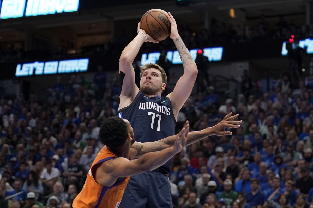 Phoenix Suns guard Cameron Payne defends as Dallas Mavericks guard Luka Doncic (77) takes a shot in the second half of Game 4 of an NBA basketball second-round playoff series, Sunday, May 8, 2022, in Dallas. (AP Photo/Tony Gutierrez)