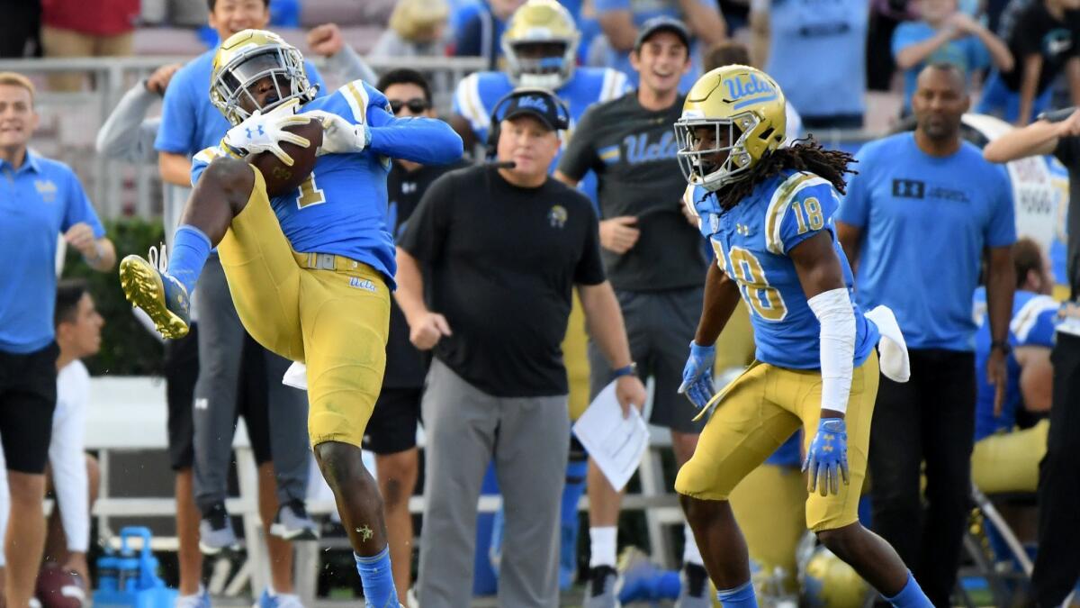 UCLA's Darnay Holmes intercepts a pass in front of teammate Elijah Gates.