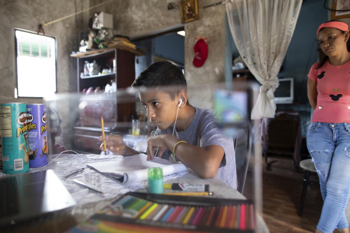 Samuel Andres Mendoza looks at a picture of a Pokemon on his computer before drawing it, at his home in Barquisimeto, Venezuela, Tuesday, March 2, 2021. The 14-year-old has been selling his drawings on his Twitter account to help the family get by. (AP Photo/Ariana Cubillos)